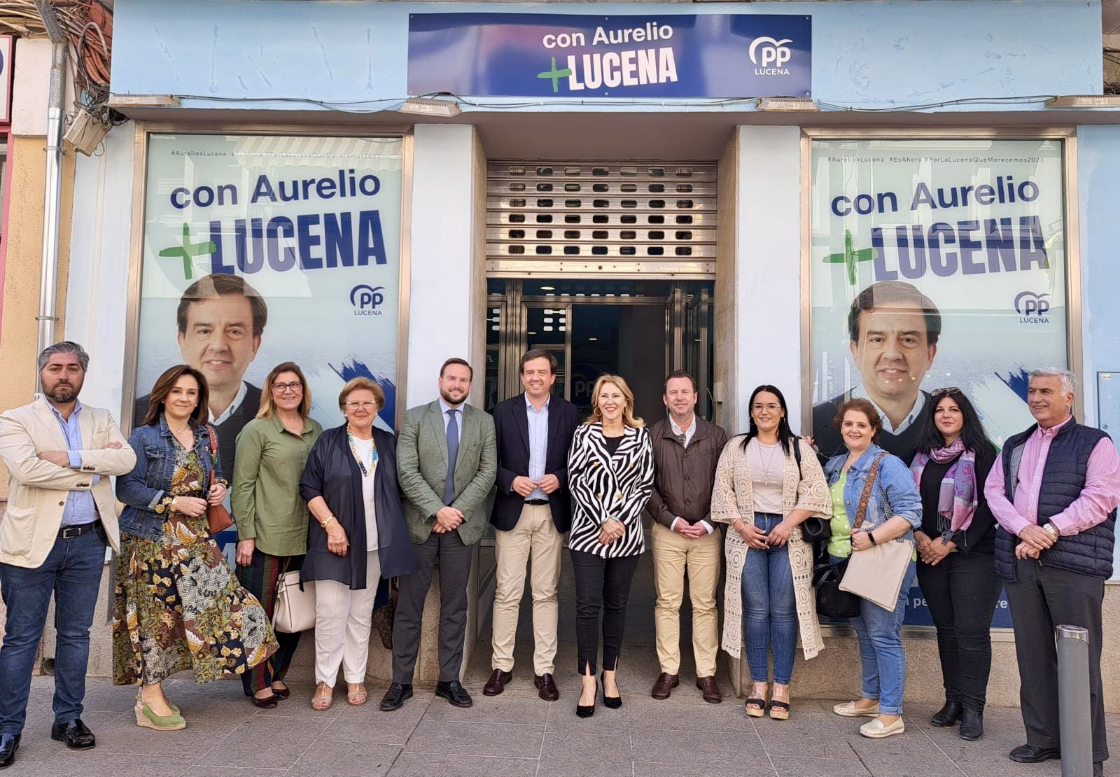 Representantes del PP junto a la Consejera de Economía, Carolina España, junto a los carteles electorales del PP en un local de la calle Juan Valera, cuya retirada ha sido exigida por la Junta Electoral Provincial