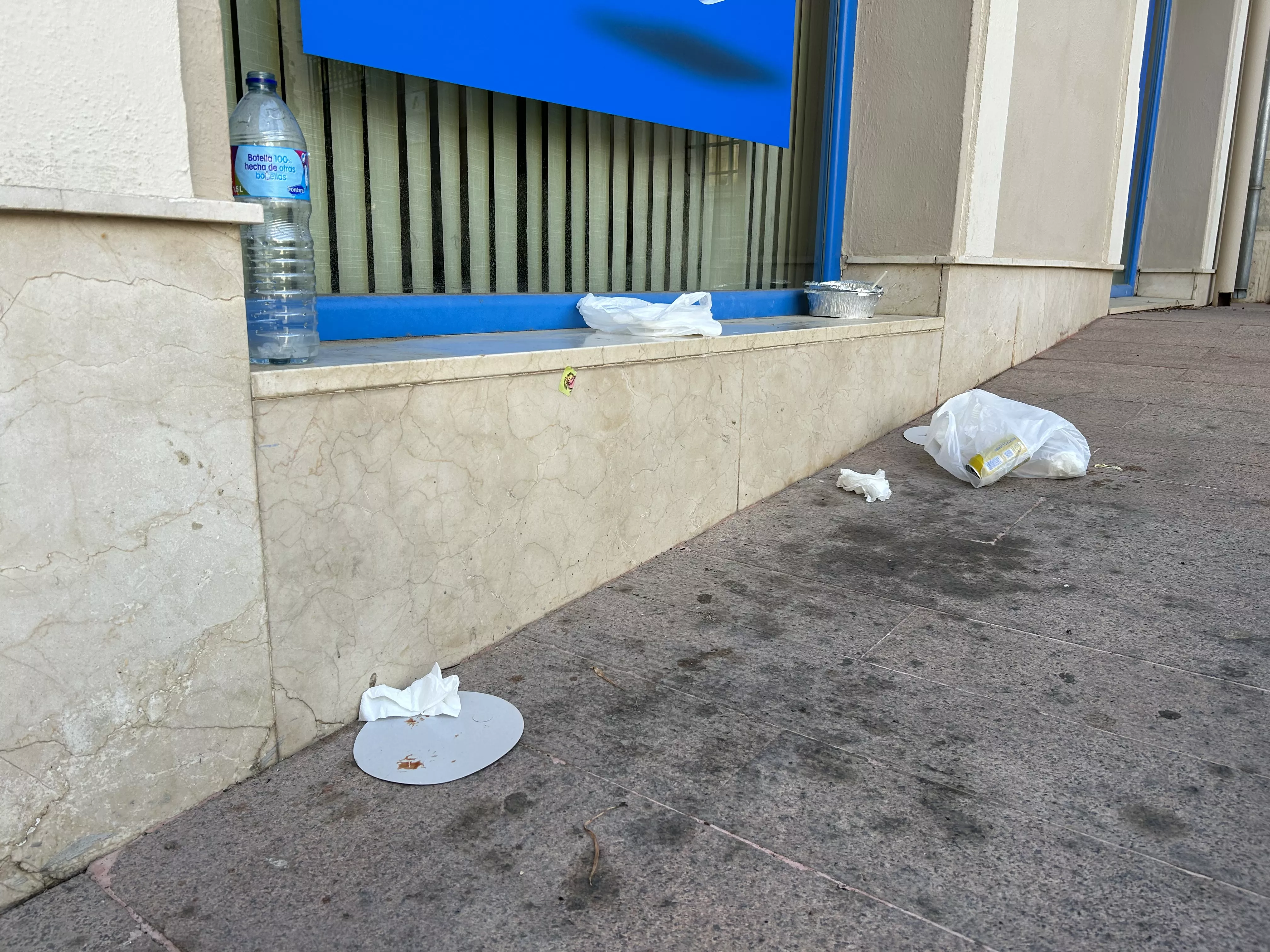 Restos de la "cena" de ayer, abandonados junto al escaparate de un comercio en el Plaza de Bécquer