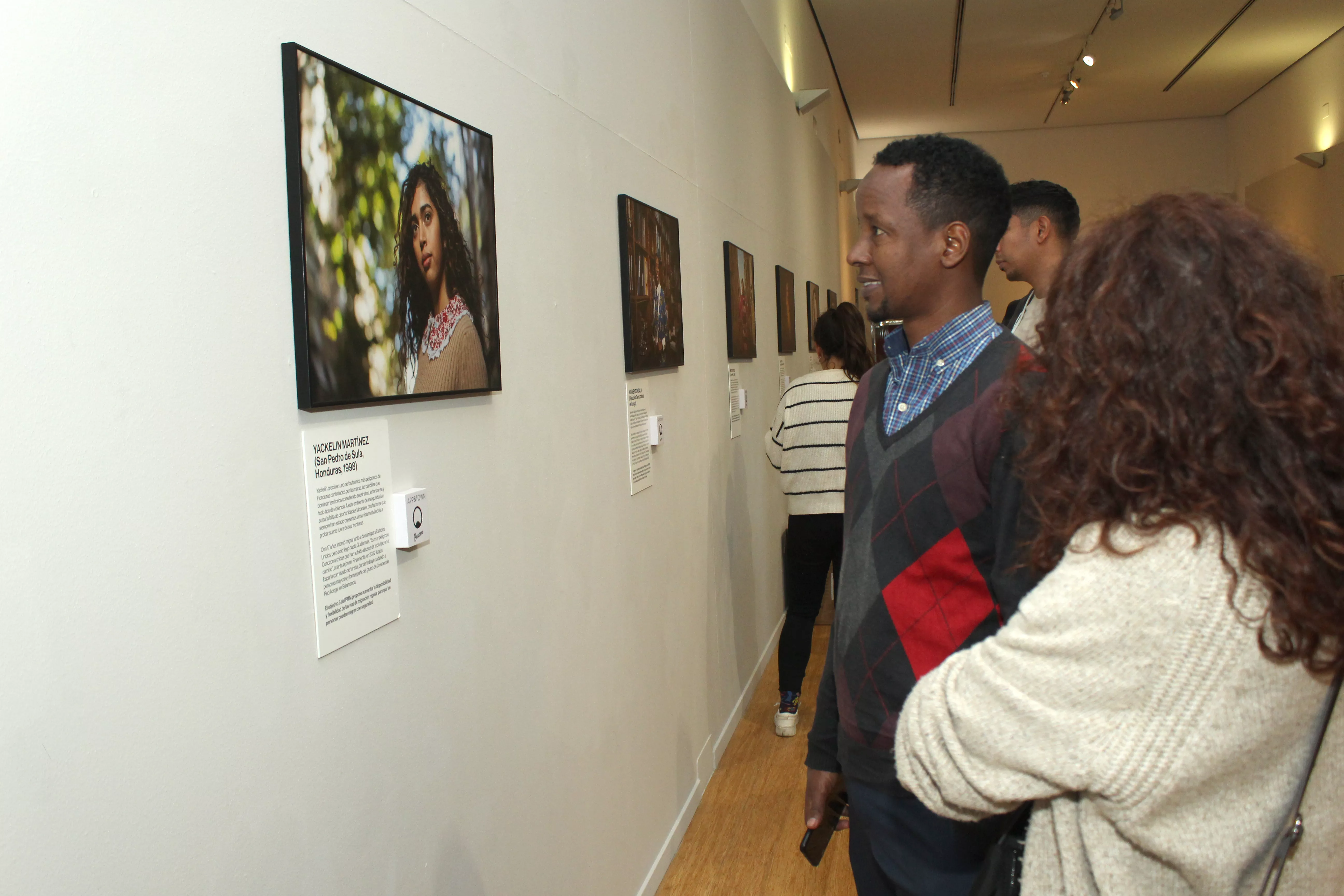 Varias personas observan el material de la exposición fotográfica ‘Vidas Migrantes’ 