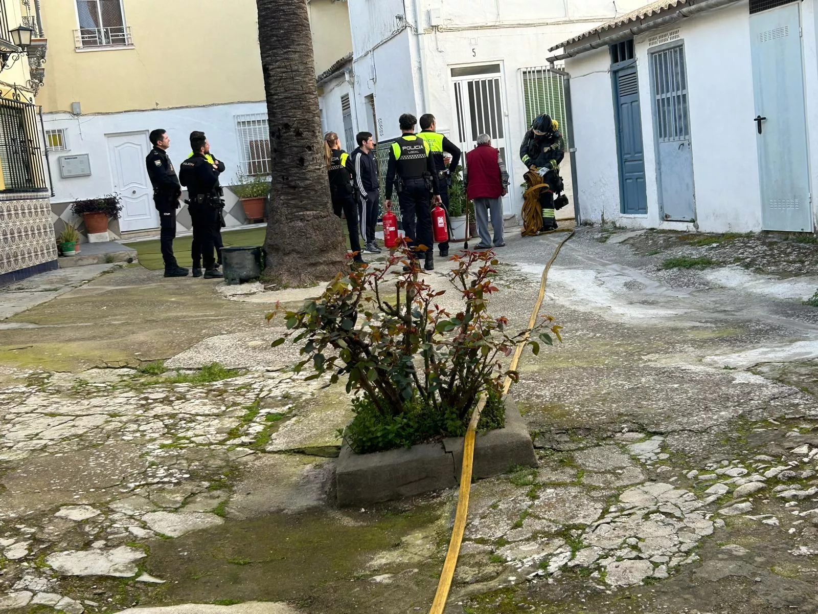 Bomberos y agentes tras la extinción del incendio de esta tarde en "Los Pabellones" de la calle Huertas