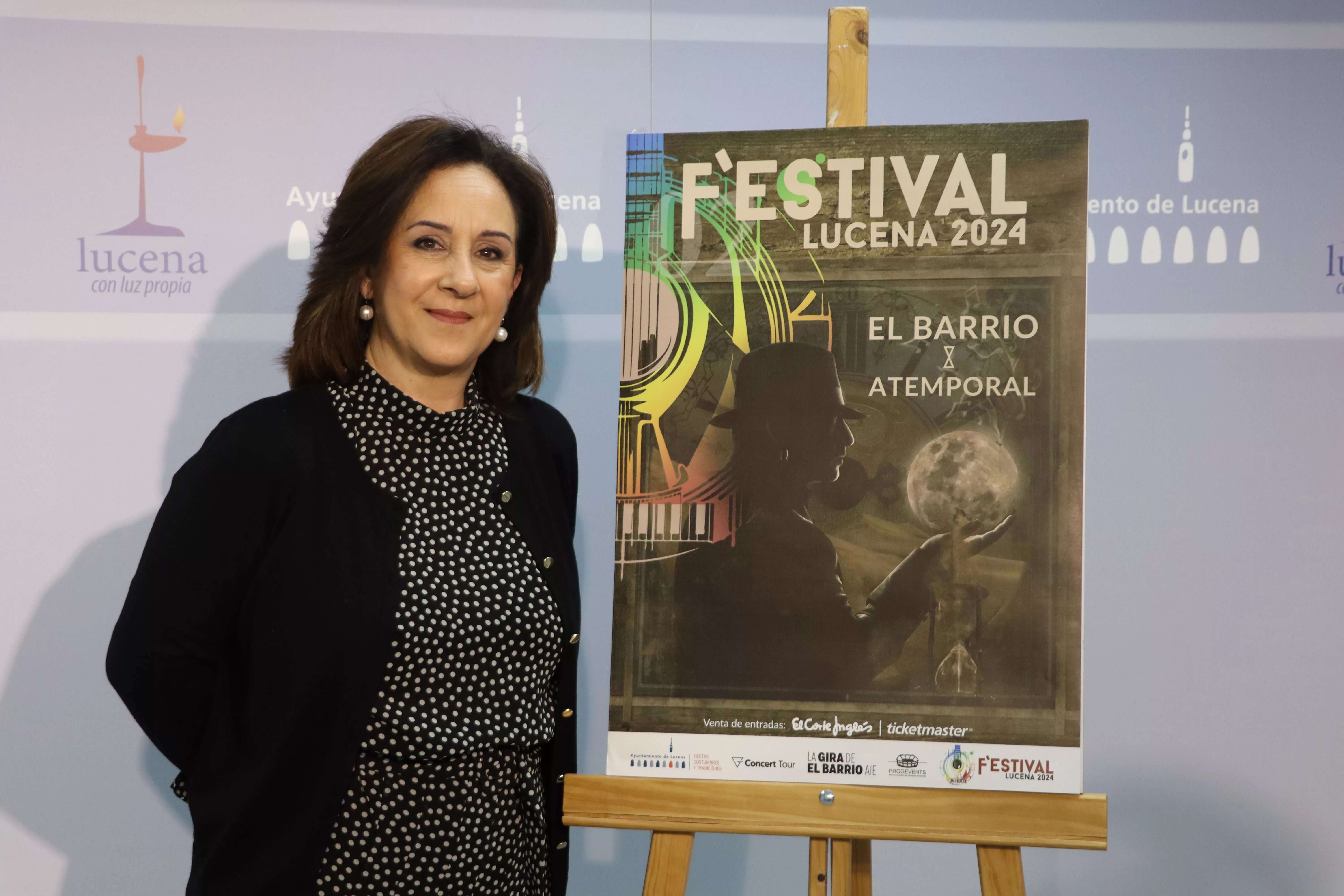 Araceli Rodríguez, edil de fiestas, junto al cartel anunciador del concierto de El Barrio en Lucena