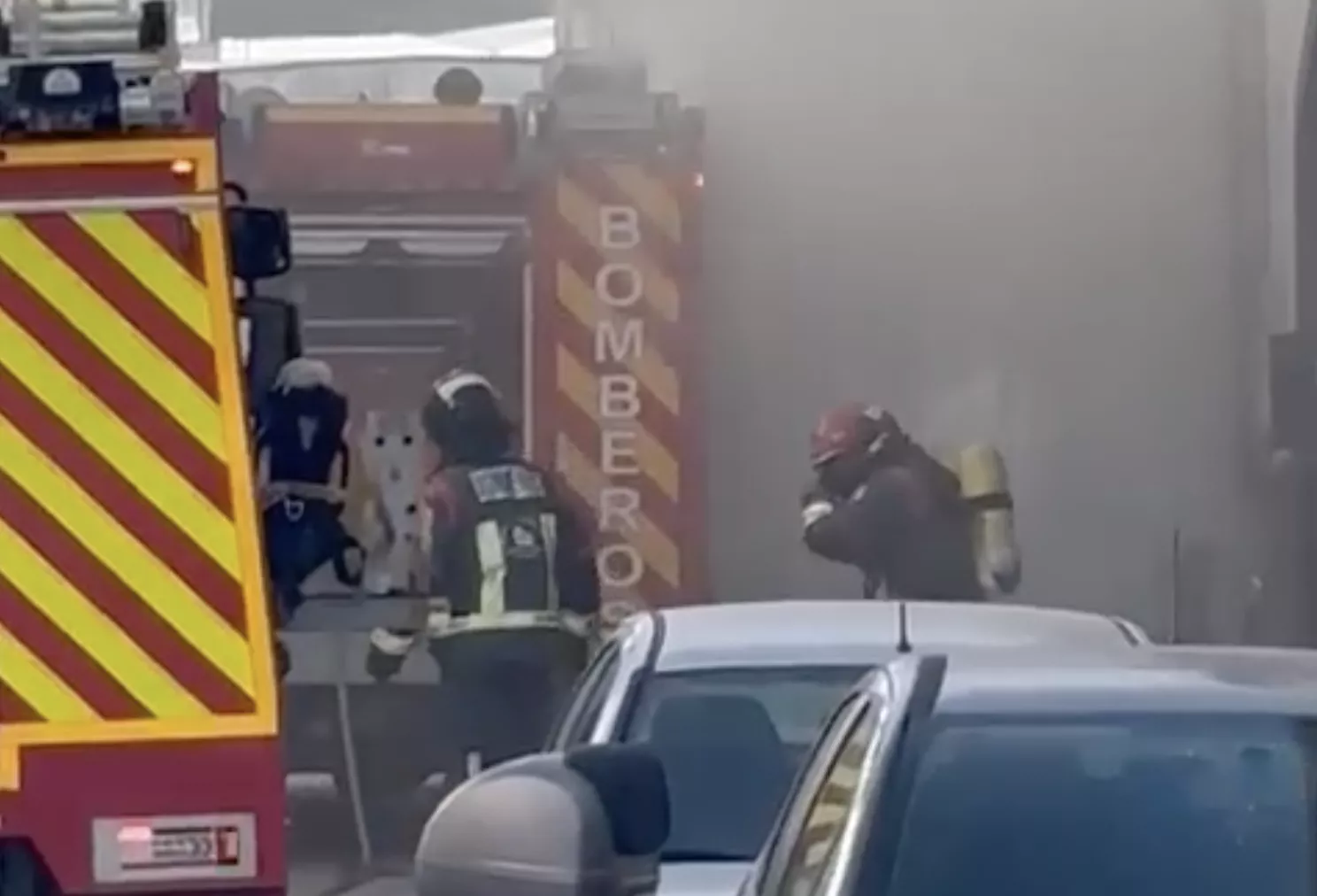 Los bomberos salen de la vivienda de la calle Montoro en la que se ha producido el incendio entre una nube de humo