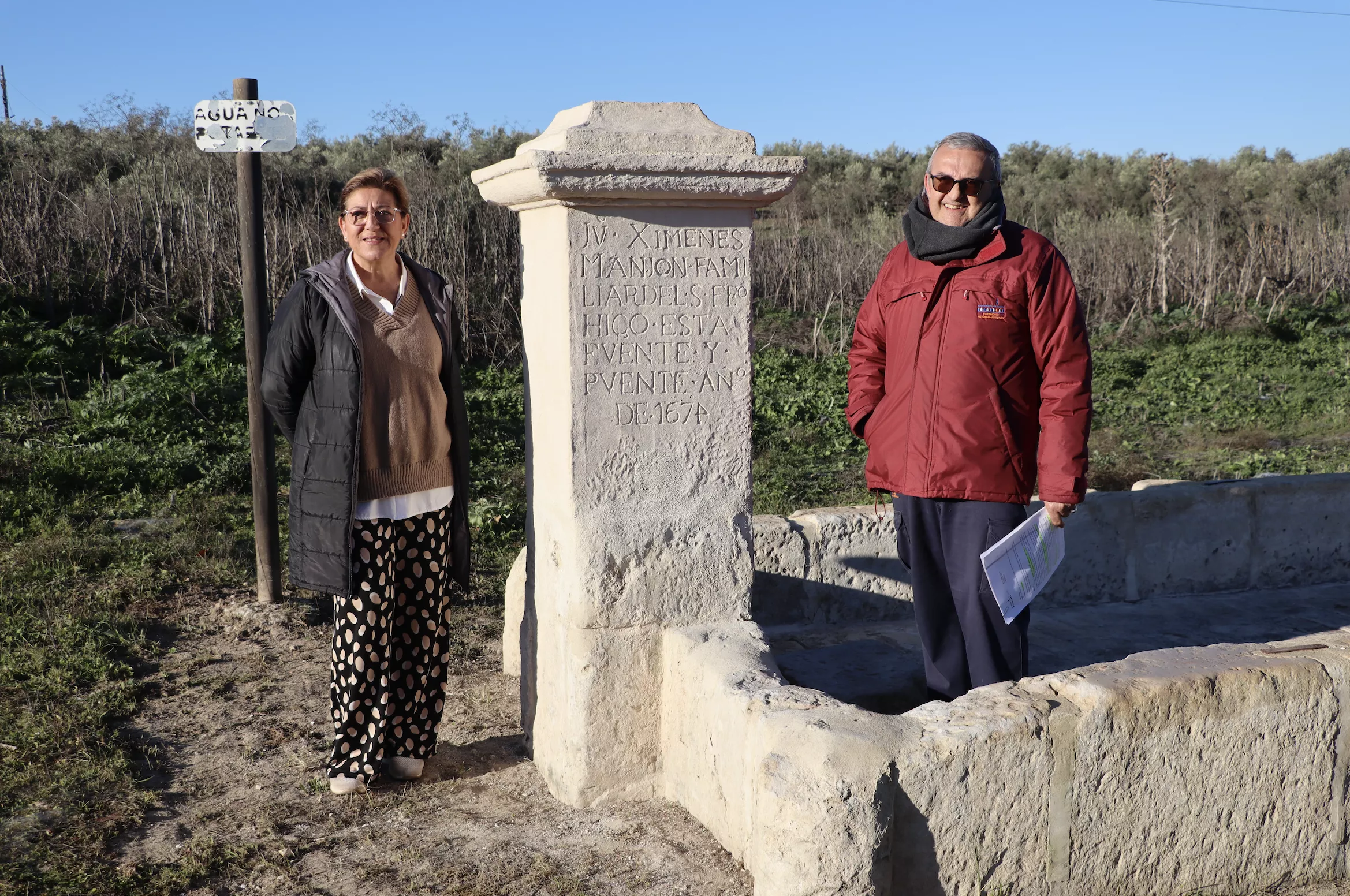 Charo Valverde y Daniel Botella junto a la réplica del pilar colocada en el abrevadero del Cortijo Grande del Duque