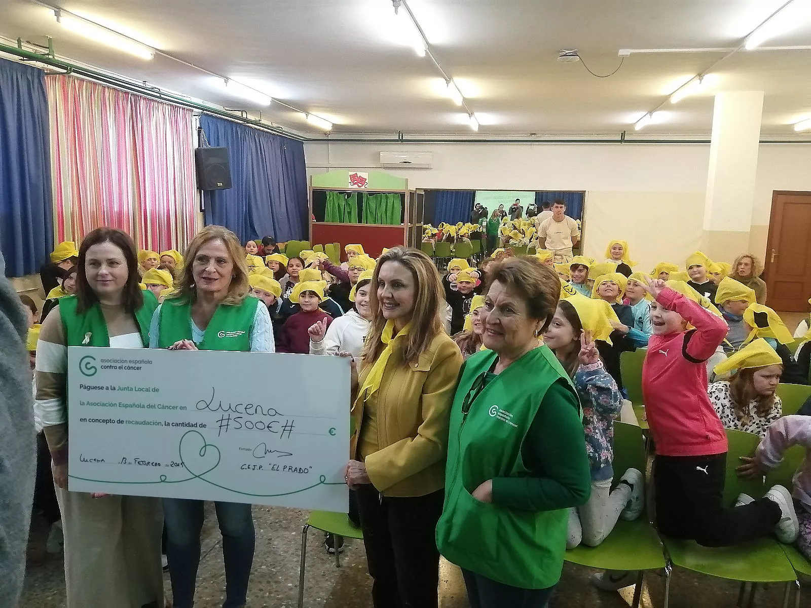 La directora del centro, María José Lara, entrega a la AECC el dinero recaudado a través de la venta de los pañuelos amarillos