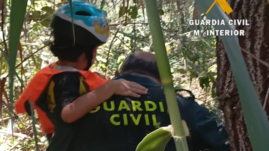 Un agente lleva a uno de los menores rescatados. 