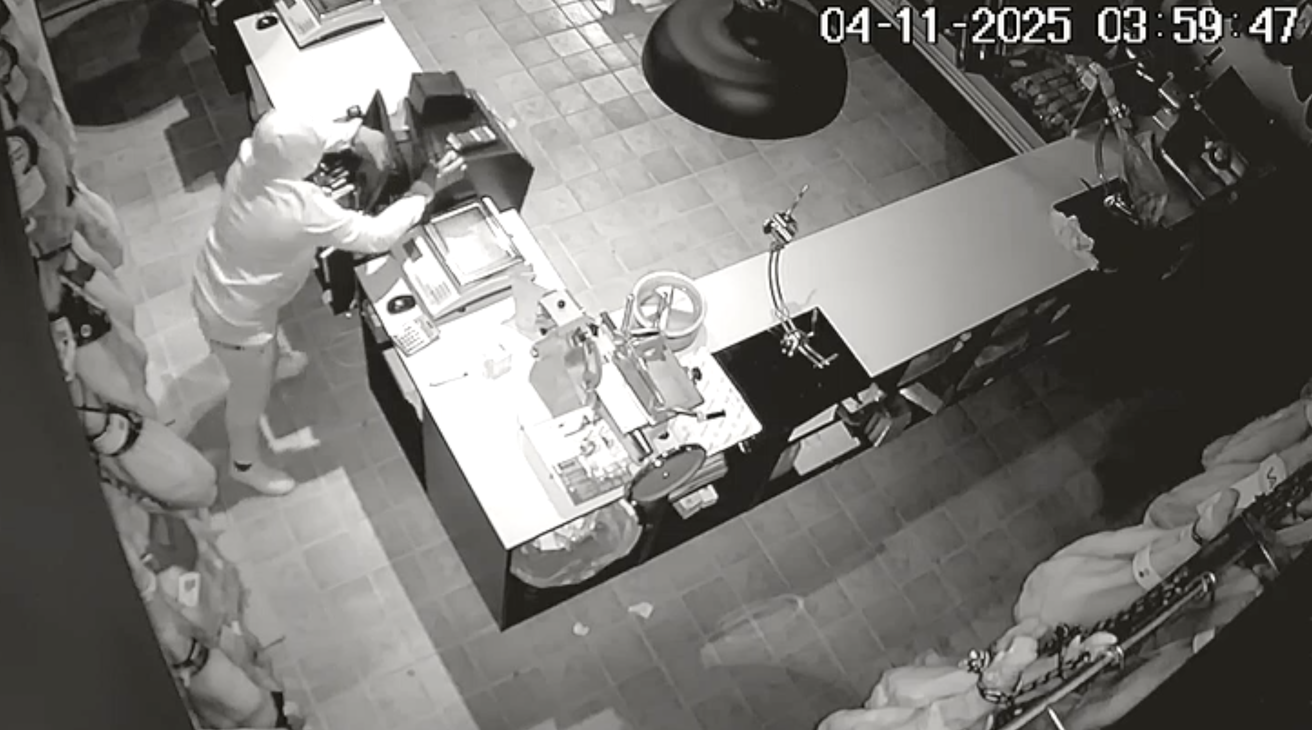 Uno de los asaltantes intenta derribar la caja registradora de seguridad del establecimiento