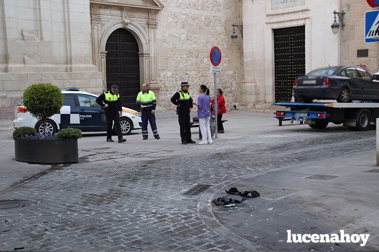  Uno de los coches accidentados sobre la grúa, mientras la policía practica las diligencias. En la foto inferior el segundo vehículo implicado, junto a la papelera que arrastró en su recorrido. 