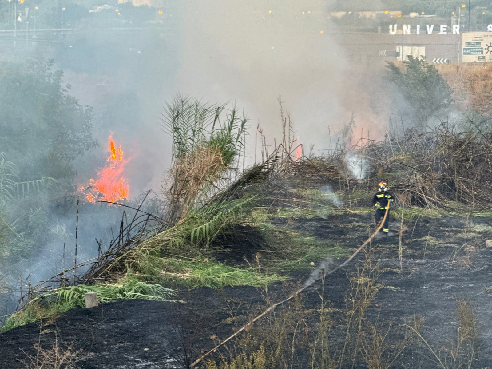Un bombero ataca las llamas junto a la ribera del río