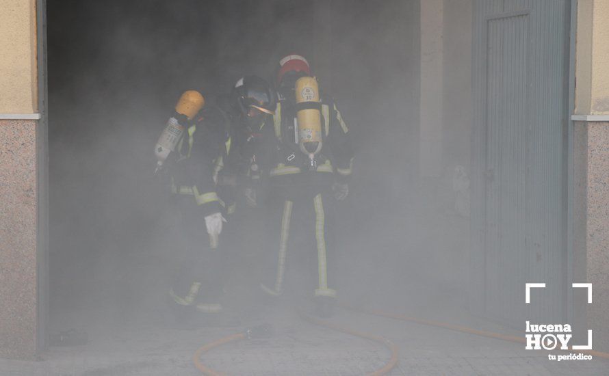  Dos bomberos salen del interior de la cochera en la que se ha producido el incendio 