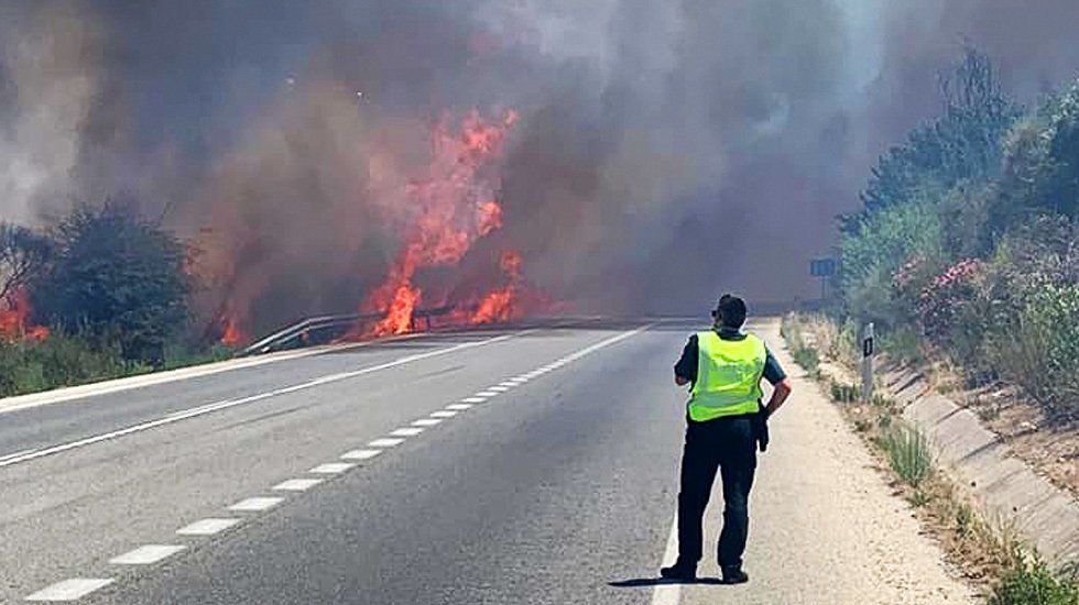  Un agente observa el avance de las llamas, ayudadas por el viento, en la A339 dirección Priego, que tuvo que ser cortada durante parte de la tarde de ayer. 